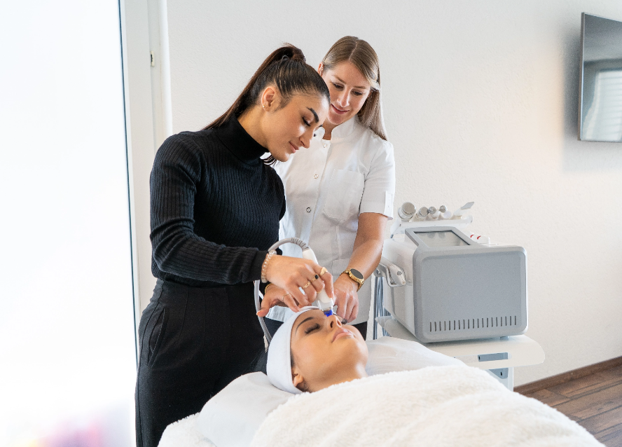 Une formatrice montre comment utiliser la machine hydrafacial à une femme pour un soin du visage